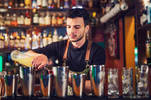 istock Young bartender at bar counter preparing a cocktail. 1143080991