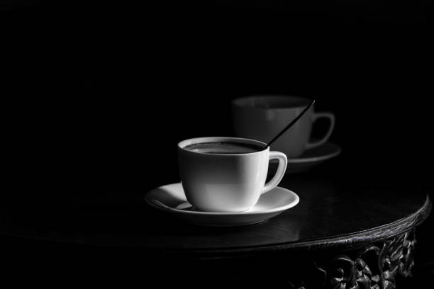 White cup of black coffee on black background - black and white rendering\n- coffee for two, copy space is plenty