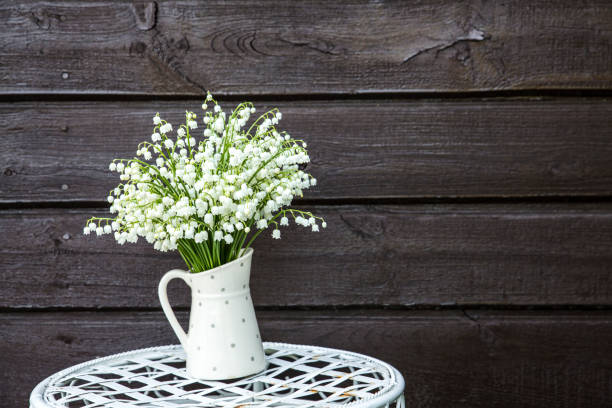白い花の花束の谷のユリ (スズラン majalis) も呼ばれます: 5 月の鐘、私たちの女性の涙と白い点線の水差し形の花瓶でメアリーの涙、派手な花のスタンドの上に屋外。 - cut flowers bouquet flower flower arrangement ストックフォトと画像