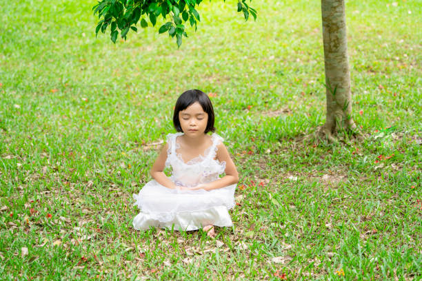 Kids girl meditating and concentration on grass in park