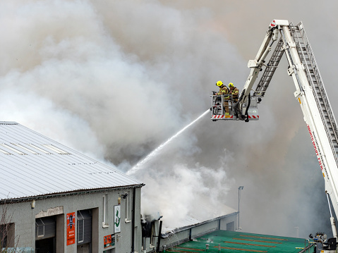 Aberdeen, Scotland, UK - 13th Apr, 2019 : Firefighters using a hose to pour water on a fire at a warehouse near Aberdeen, Scotland.