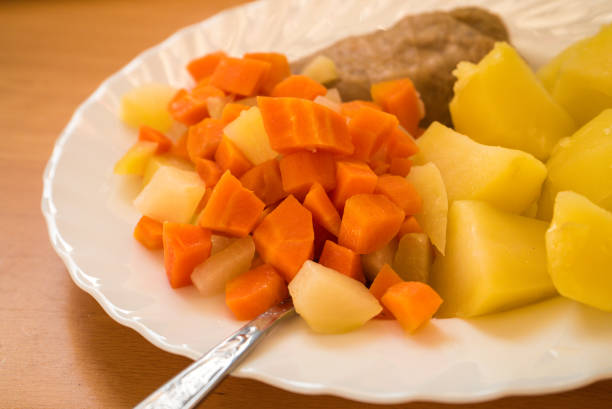 Close up of food an plate. Dinner meal, braised carrot, boiled potatoes and meat