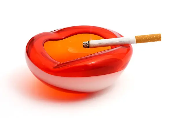Photo of Retro red and white ashtray with lit cigarette