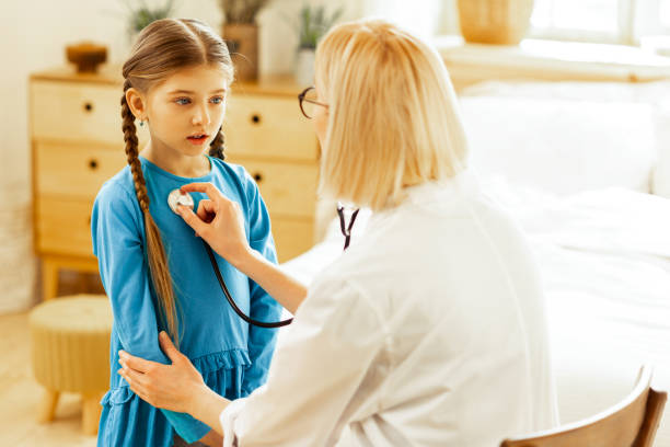 istock Pretty girl standing quietly while pediatrician examining her lungs. 1143088803