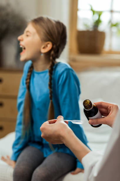 istock Small sick mischievous girl loudly refusing to take throat syrup 1143088831