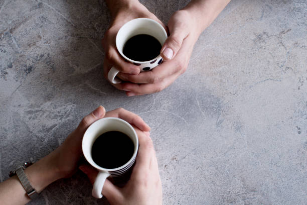 istock Man and woman hands holding coffee cups on grey background. 1143090323