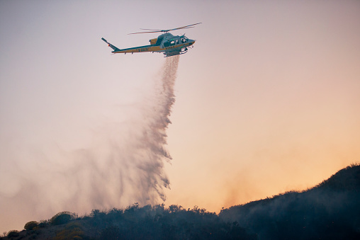 Helicopter dumping water over a los angeles wild fire