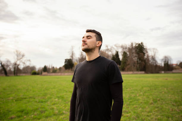 Man relaxing and breathing fresh air in a city park .Handsome man deep breathing in a sunny spring day. Recreational activities concept.