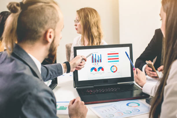 istock Business professionals. Group of young confident business people analyzing data using computer while spending time in the office 1143092666