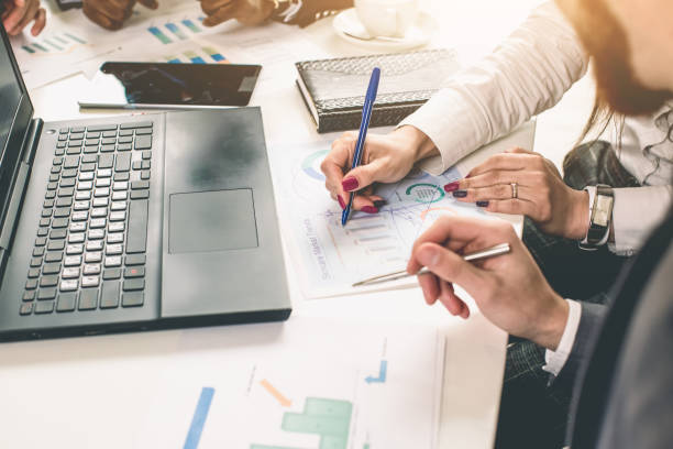 istock Business professionals. Group of young confident business people analyzing data using computer while spending time in the office 1143092681