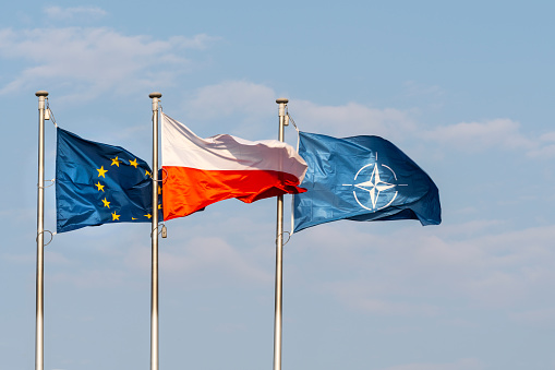 Warsaw, Poland. April 2019.   The flags of Poland, Europe and NATO waving on a blue sky