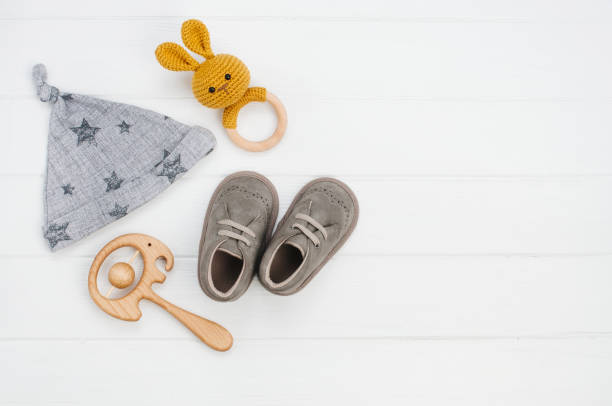 istock Baby hat, booties and wooden teether on white wooden background 1143098197