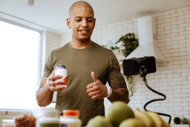 istock Bodybuilder showing thumb up while filming video about vitamins 1143103417