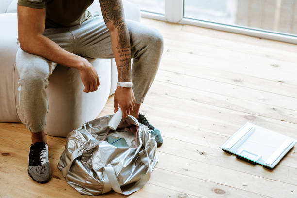 sportsman with tattoo on hand packing his bag for gym - gym bag imagens e fotografias de stock