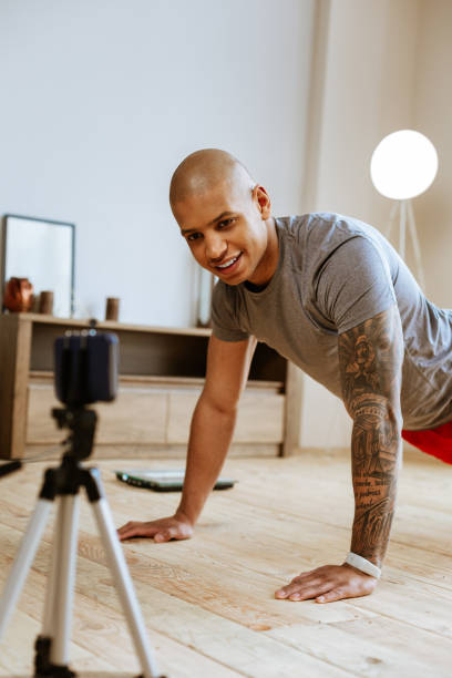 istock Dark-skinned sportsman showing exercises while making video 1143103510