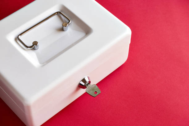 istock Closed cash box with key in lock on pink background 1143106104
