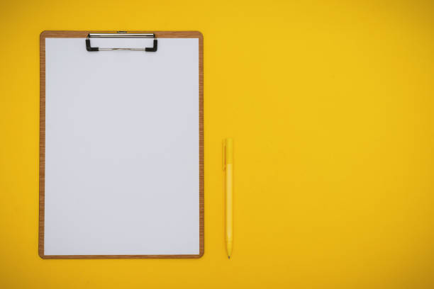 Paper on Clipboard and Pen on Yellow Background stock photo