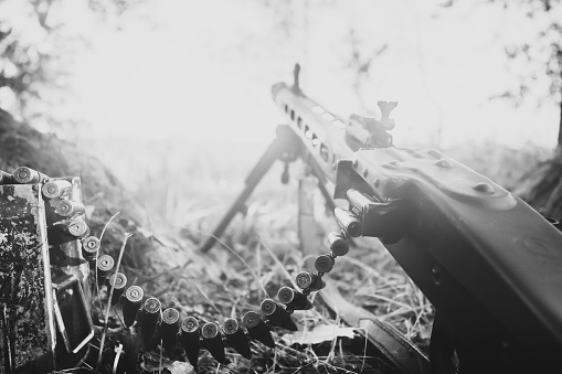World War II German Wehrmacht Infantry Soldier Army Weapon. MG 42 Machine Gun On Ground In Forest Trench. WWII WW2 German Ammunition. Photo In Black And White Colors.