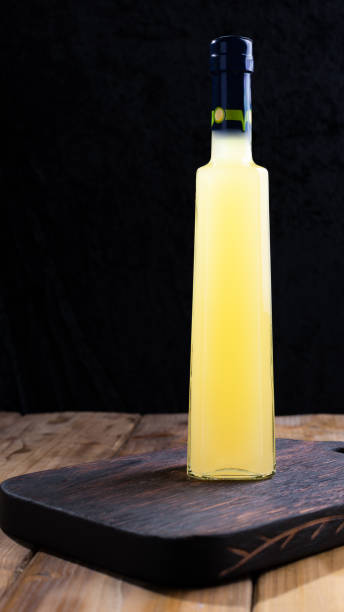 лимончелло в бутылке с пространством для этикеток и текста. традиционный итальянский лимонный ликер. алкоголь на темном фоне. вертикальное - neapolitan specialty стоковые фото и изображения