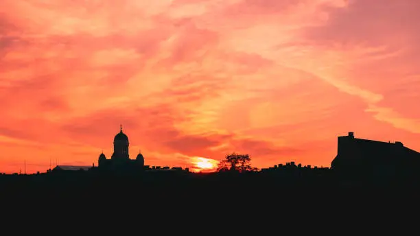 Photo of Helsinki, Finland. Famous Landmark Is Lutheran Cathedral In Evening Lighting. Dark Silhouette Of Cityscape Skyline In Backlit At Sunset On Colourful Orange And Yellow Colours Dramatic Sky