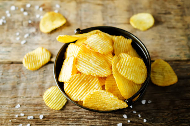 Potato chips with salt on a wood background stock photo