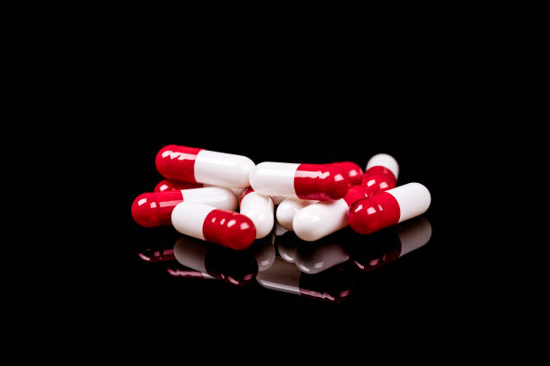 Closeup of  white - red capsules isolated on black background. - Image