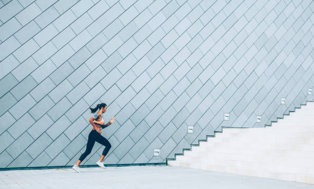 woman is running on the city stairs - determination running staircase jogging imagens e fotografias de stock