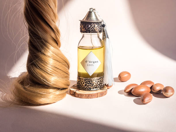 影のフレームを持つ太陽の自然光の下で貴重なモロッコのアルガンオイルとナッツと伝統のモロッコ風でエンボス加工した金色の髪と装飾ボトルのカール - アルガンオイル ストックフォトと画像