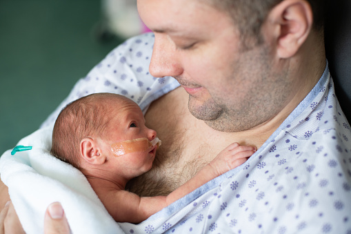Padre cuidando de su bebé prematuro haciendo piel a la piel en el hospital photo