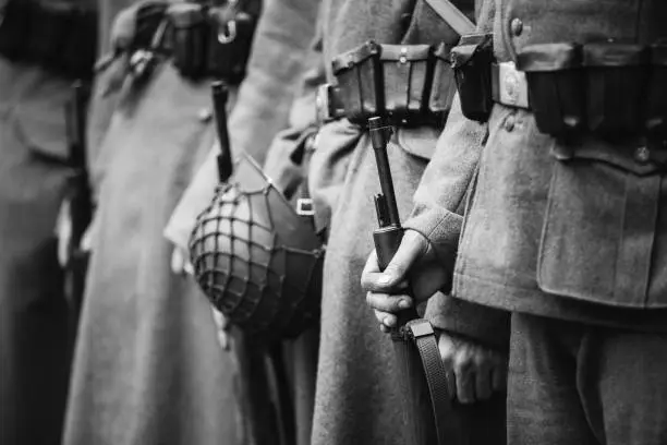 Re-enactors Dressed As World War II German Wehrmacht, Soldiers Standing Order With Rifle Weapons In Hands. Photo In Black And White Colors. Soldiers Holding Weapon Rifles.