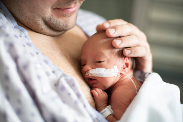 Father taking care of his premature baby doing skin to skin at hospital stock photo