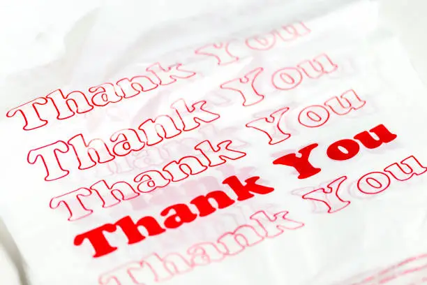 Stack of new plastic shopping bags with red Thank You text.