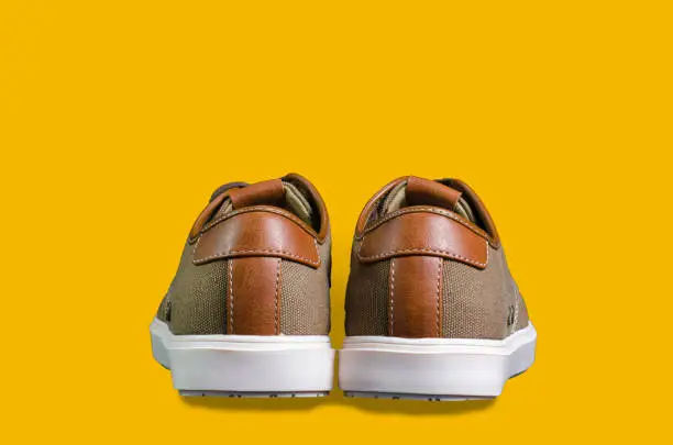 Photo of Canvas and leather sneakers isolated on color background