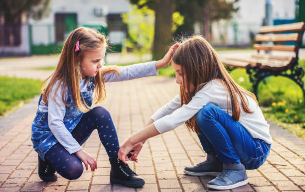 友人のためのヘルプとケア。もう一人の小さな女の子の女の子の抱き合わせ - child spring family little girls ストックフォトと画像