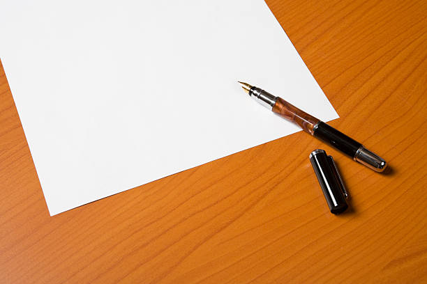 A ballpoint pen rests on top of a stack of documents ready for signing.  The image is photographed using a very shallow depth of field with the focus being on the tip of the pen.