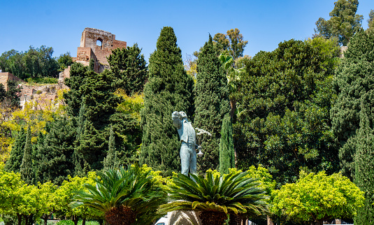 Spain, Malaga - 04.04.2019: El Biznaguero statue in the Pedro Luis Alonso Garten in Malaga Spain with Alcazaba background daytime