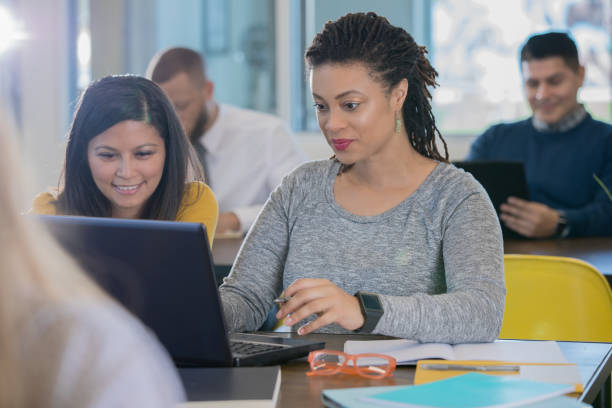 istock Diverse millennial businesswoman using laptop together in collaborative workspace 1143163409