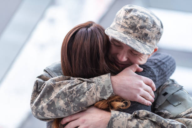 Man hugging his wife after returning home from service A handsome man dressed in a military uniform passionately hugs his partner as he greets her returning from his military service in this close-up. wife stock pictures, royalty-free photos & images
