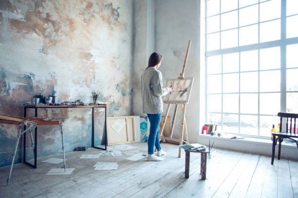 Young woman artist painting at home creative standing drawing Young woman artist painting at home standing drawing near the window inspiration full body messed room drawing art product photos stock pictures, royalty-free photos & images