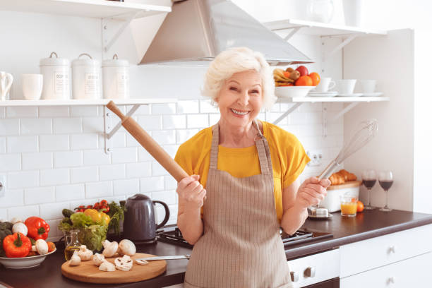 istock Old housekeeper laughs holding a rolling pin and a whisk 1143163624