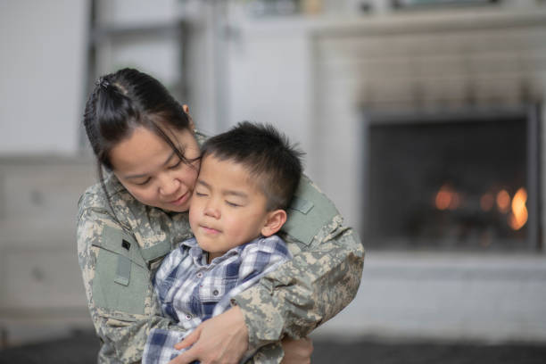 Upset Child A mother wearing a military uniform is hugging her son. The son looks upset that his mother is leaving. filipino family reunion stock pictures, royalty-free photos & images