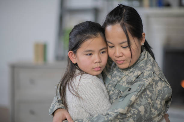 Saying Goodbye A military woman is hugging her daughter in their living room. The girl looks sad to see her mom leaving. They are emotional and somber. filipino family reunion stock pictures, royalty-free photos & images