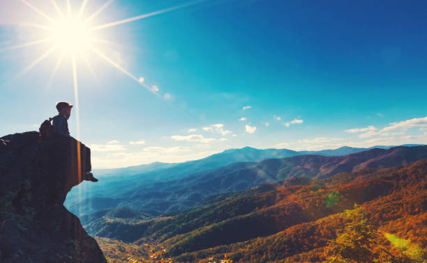 istock Man sitting on the edge of a cliff overlooking 1143164793