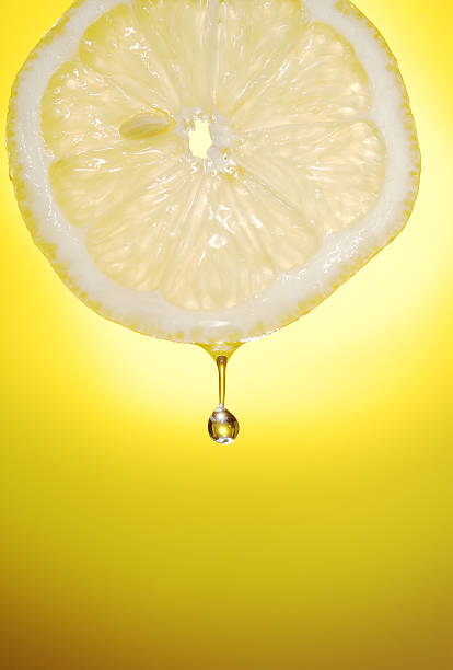 A drop of juice dripping from a slice of lemon