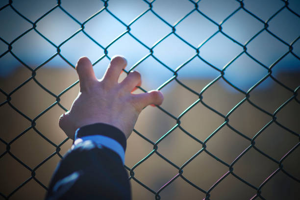 istock hand on the net fence 1143167073