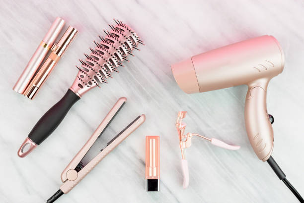 Women’s styling tools and cosmetics in rose gold Rose gold hair care and beauty products on marble countertop iron appliance stock pictures, royalty-free photos & images