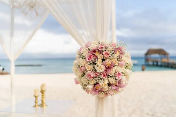 Pastel colored decoration at the Mayan Riviera with a flower bouquet, sand and a pier in the back