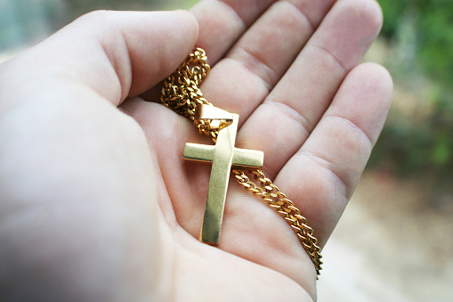 Gold Religious Cross In Palm Of Hand