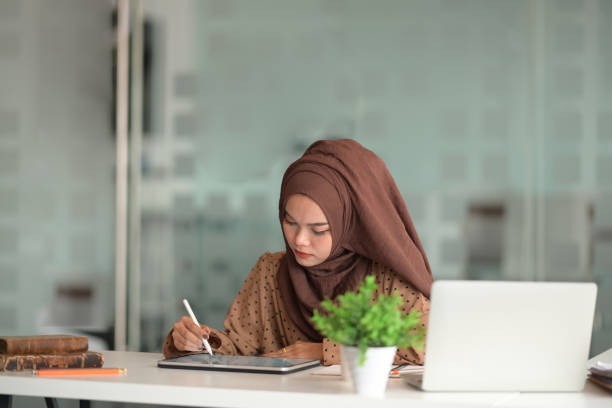 istock Asian woman in hijab using tablet and laptop in office 1143177674