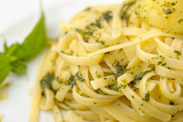 rolled boiled spaghetti with fresh basil leaves on a white background